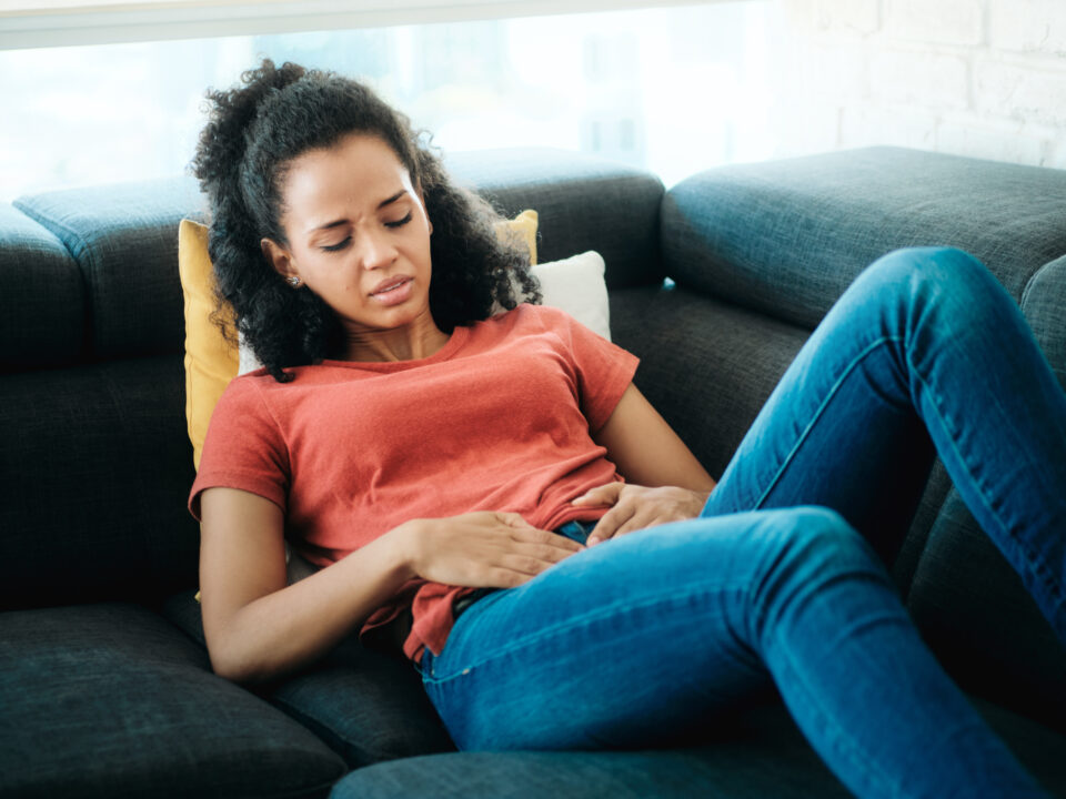 Young Black Woman With Menstrual Pain Lying On Sofa