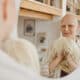 Bald Cancer Patient Smiling While Holding a Wig in Front of the Mirror